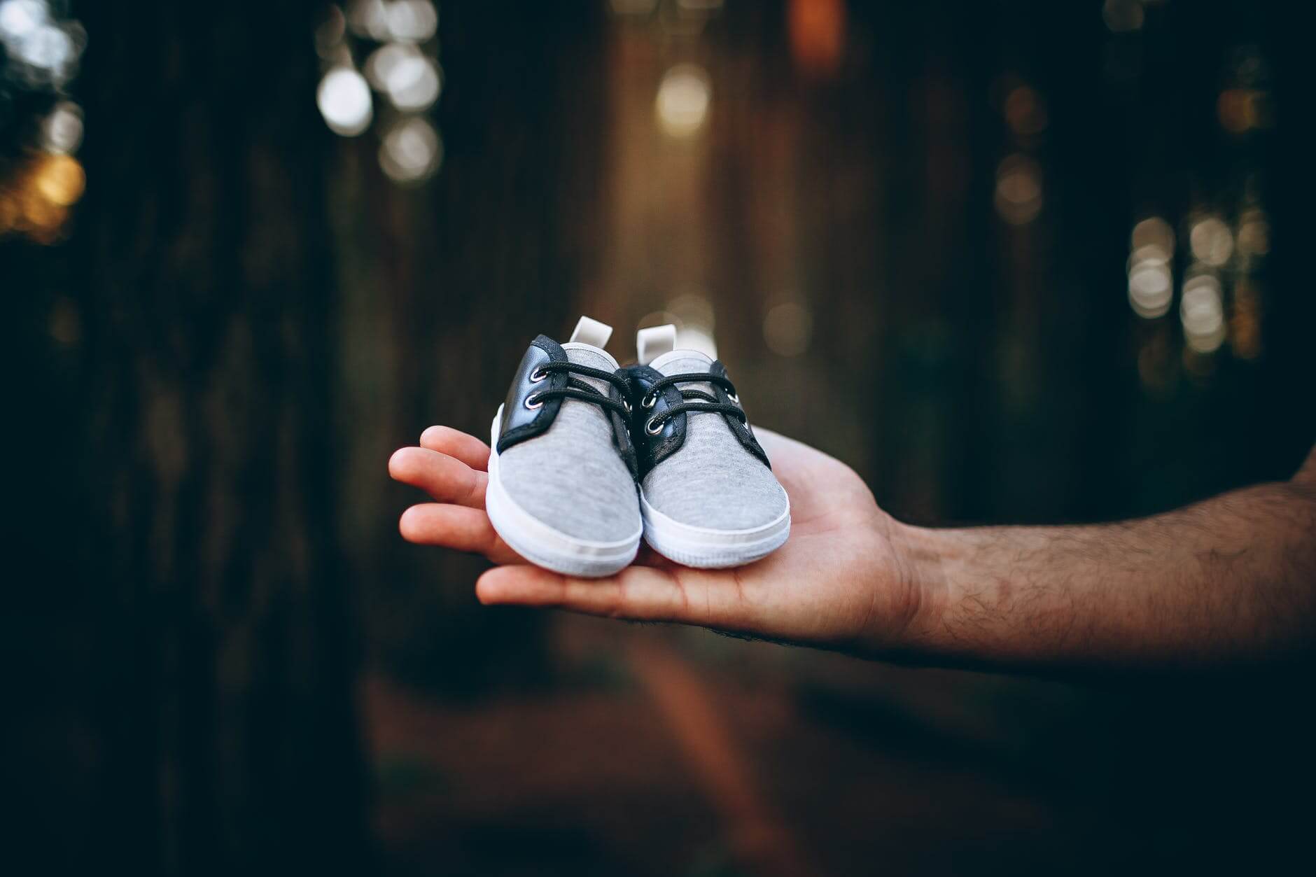 tiny sneakers on hand of man in nature