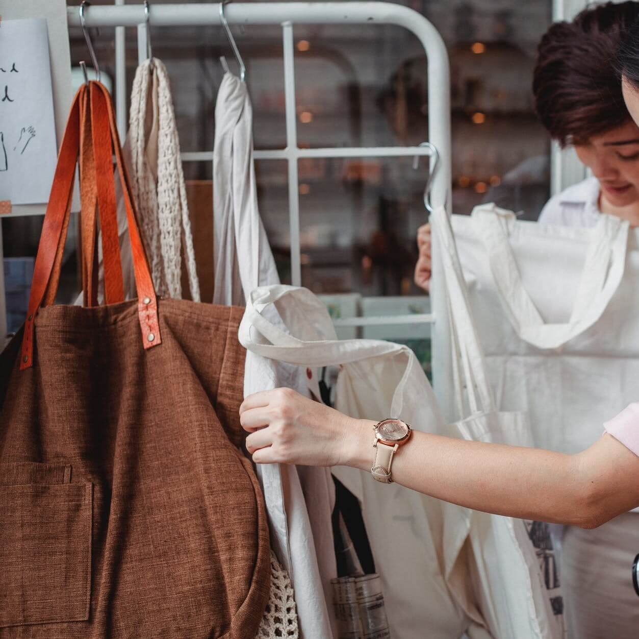 trendy young asian women choosing cotton bags in fashion boutique